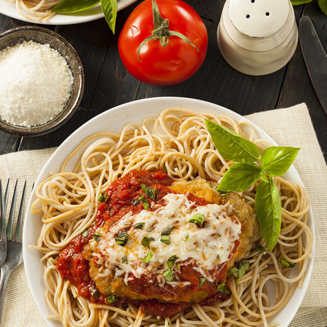 Chicken parmigiana over bed of spaghetti.