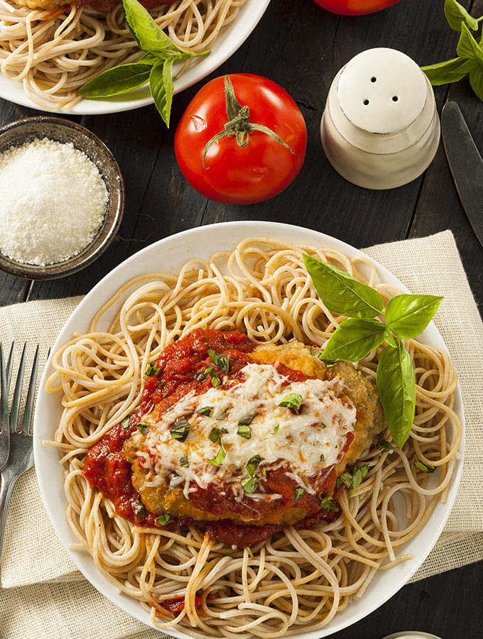 Chicken parmigiana over bed of spaghetti.